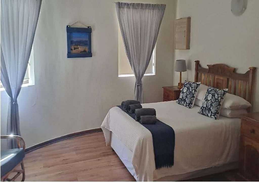 Spacious bedroom with wooden bed, patterned pillows, and folded towels
