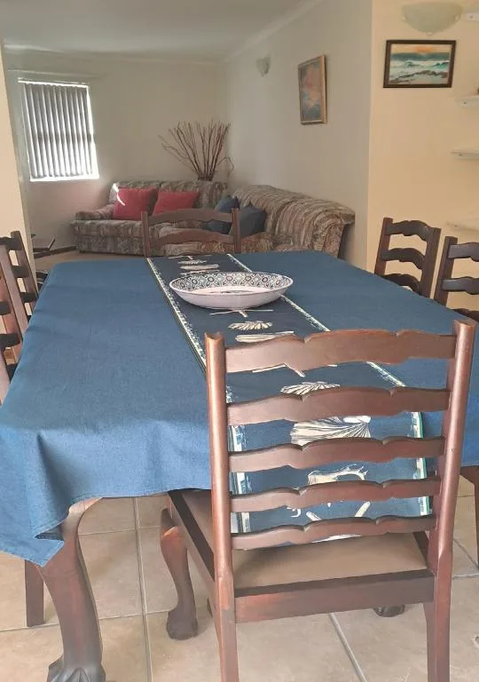 Dining table with blue tablecloth and wooden chairs in open-plan apartment