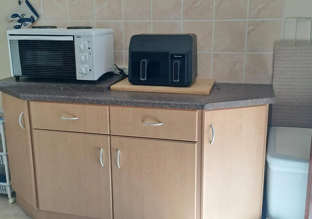 Kitchen counter with oven, toaster, and wooden cabinetry with dark countertop