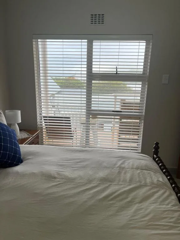 Bright bedroom with bed and large shuttered doors overlooking garden