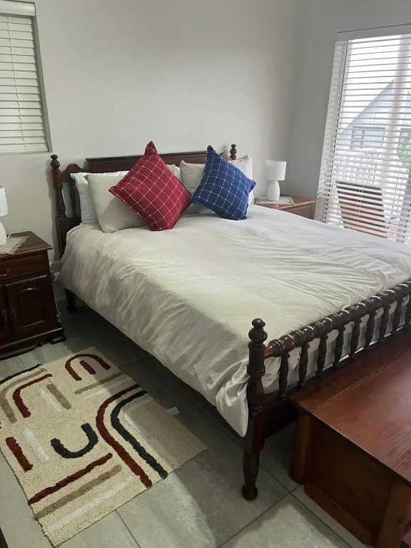 Spacious bedroom with dark wooden bed, white bedding, and colorful decorative pillows