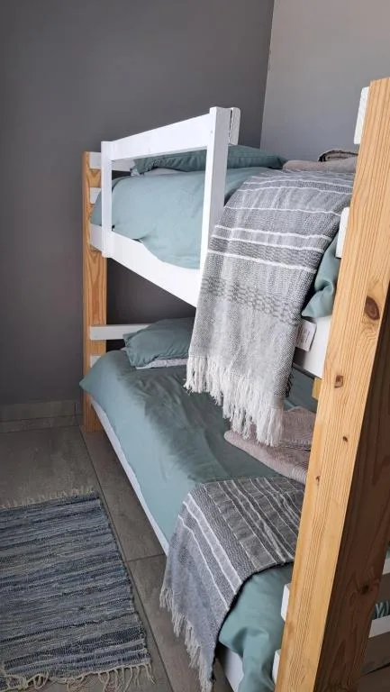 Wooden bunk bed with white frame and light blue bedding