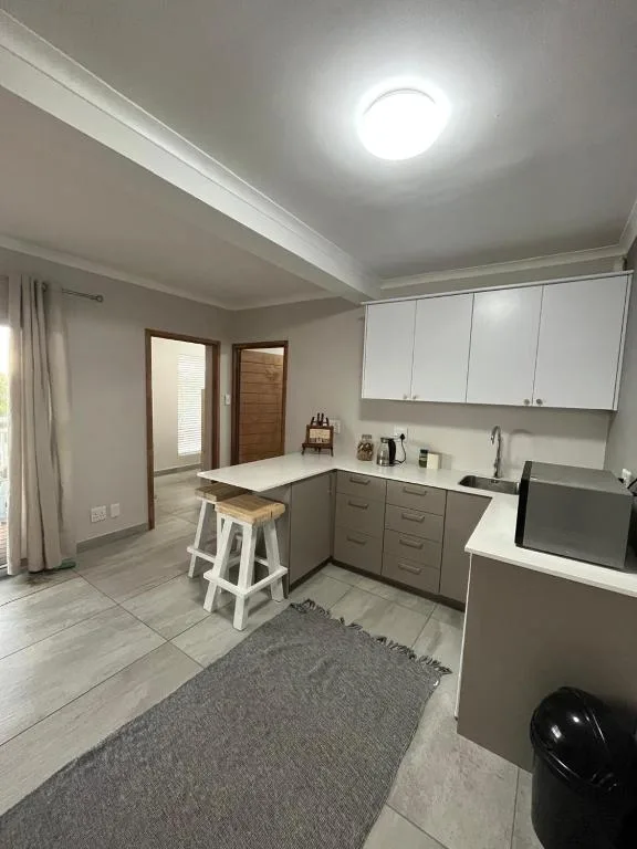 Modern kitchen with white upper cabinets, gray lower cabinetry, and white breakfast bar seating