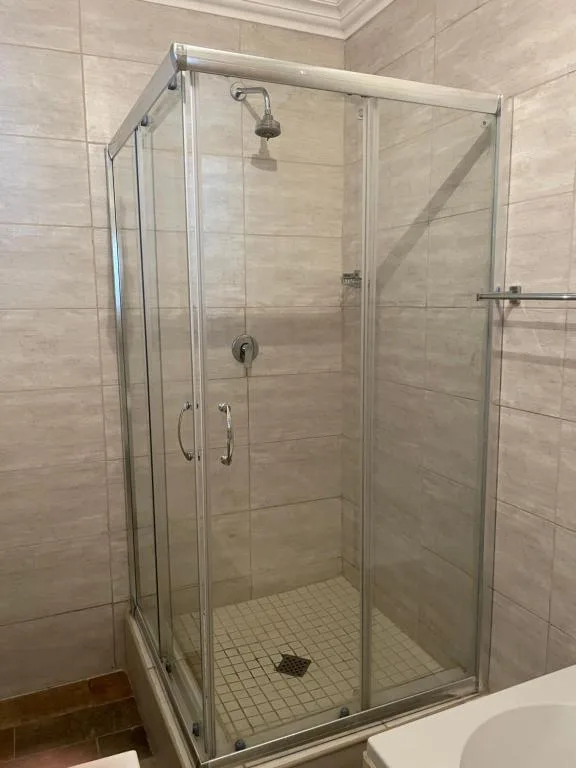 Modern glass shower enclosure with rainfall showerhead and tiled walls