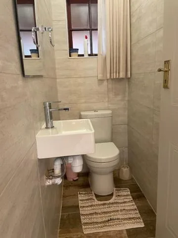 Modern bathroom with white sink, toilet, and beige tile walls