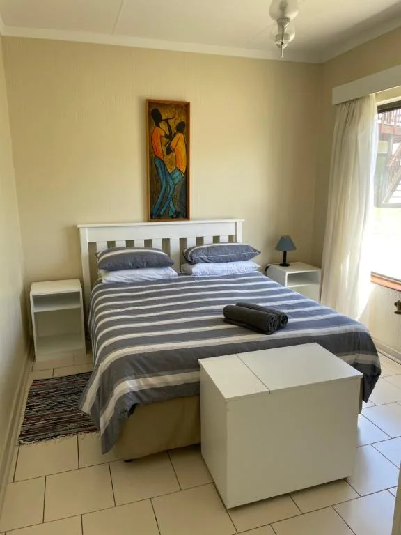 Bright bedroom with striped bedding, white nightstands, and contemporary artwork