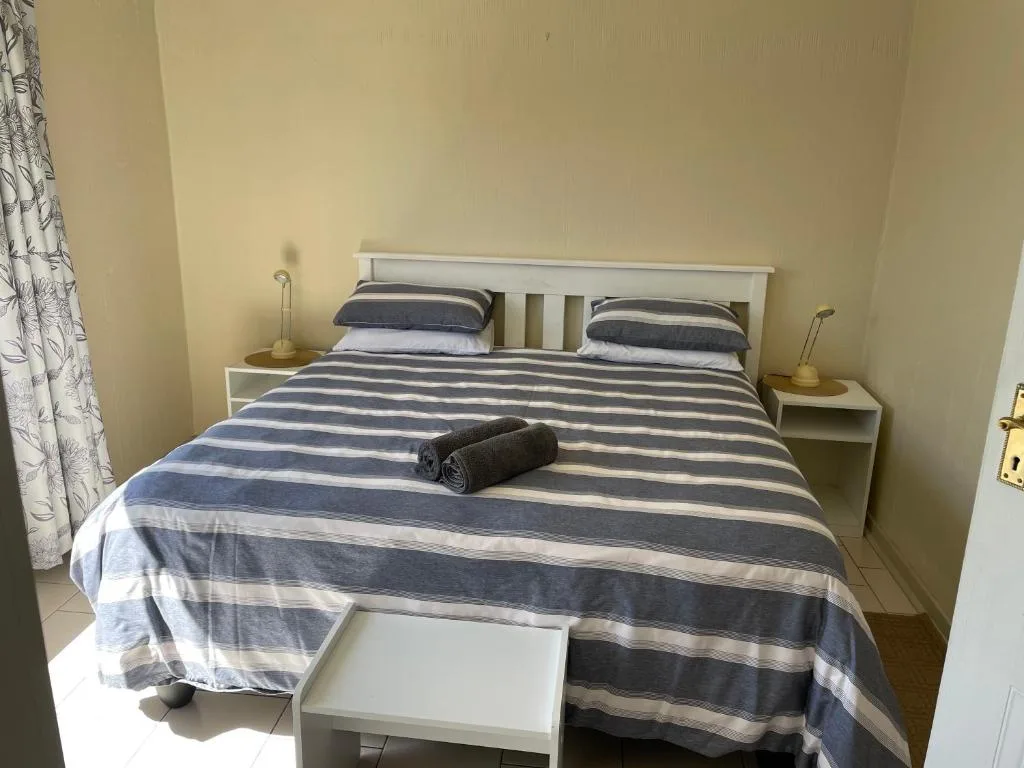 Comfortable double bed with navy striped bedding and side tables