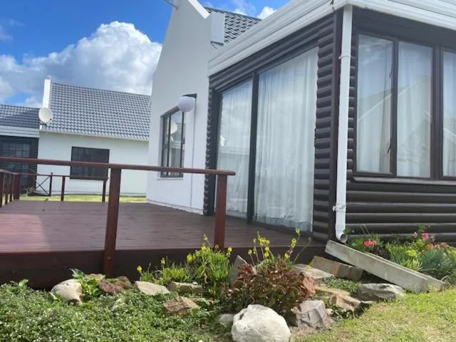 Wooden deck with brown railings extending from modern cottage exterior
