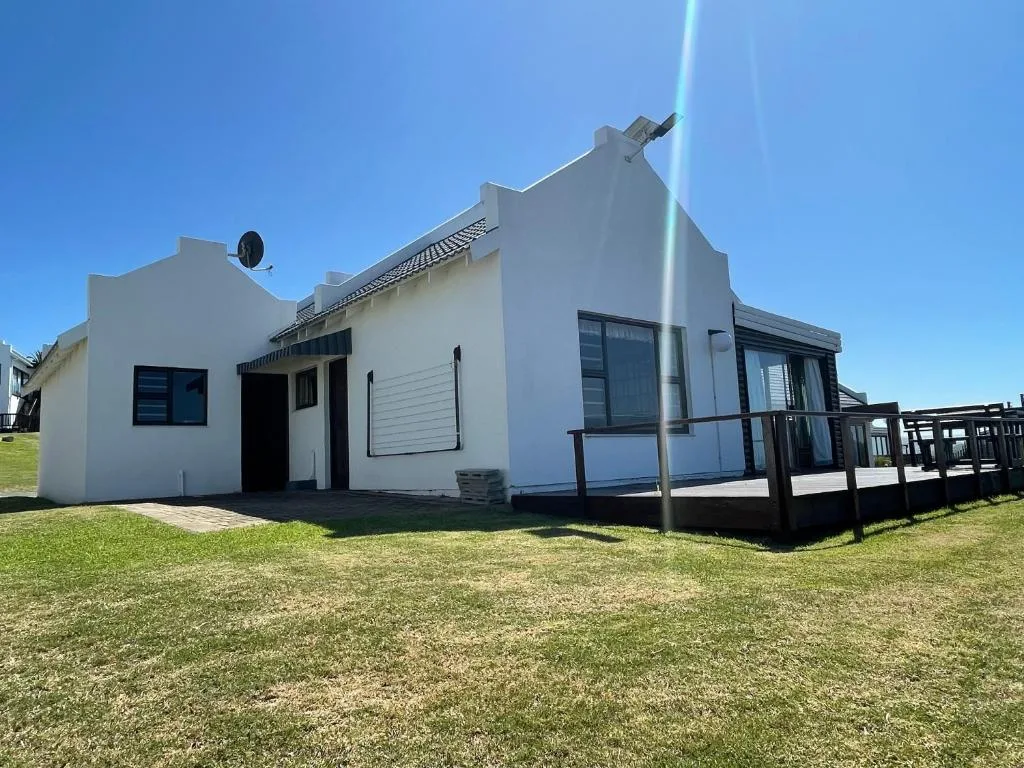Modern white holiday cottage with black deck and manicured lawn