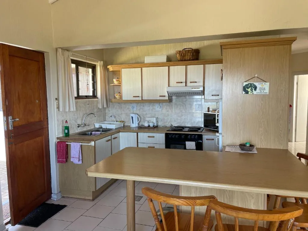 Modern kitchen with white cabinetry, gas stove, and dining counter with wooden chairs