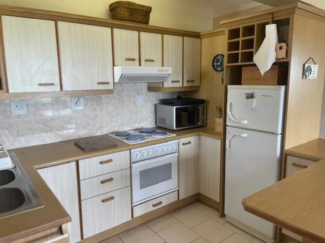 Kitchen with white cabinetry, stove, microwave, and refrigerator