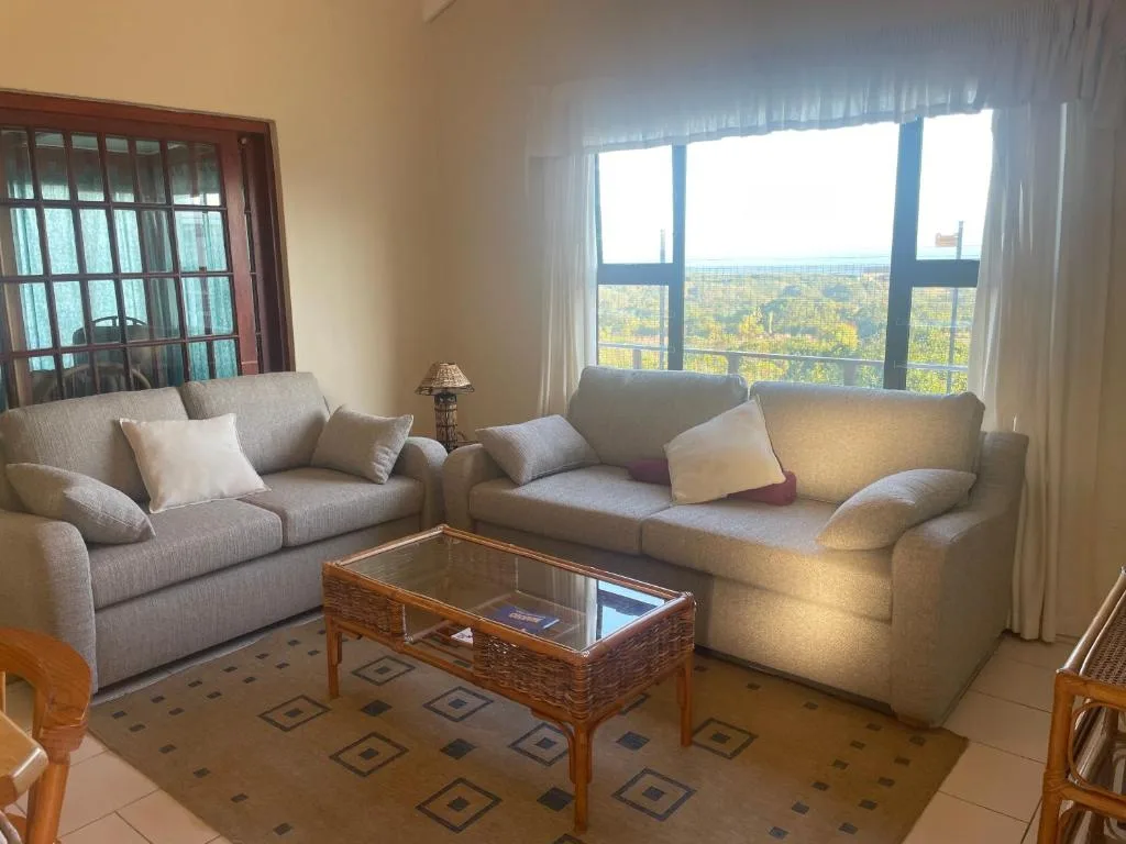 Bright lounge with gray sofas, coffee table, and expansive forested view windows