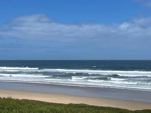 Pristine sandy beach with rolling ocean waves and blue sky