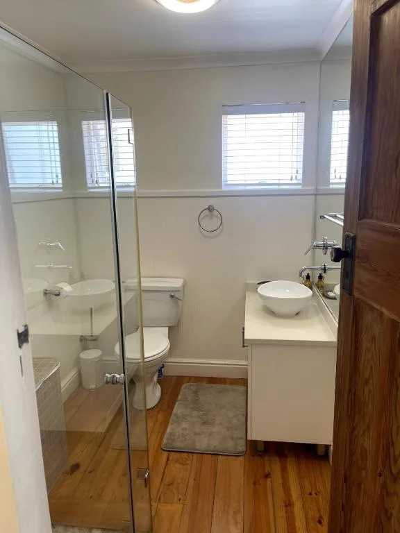 Modern bathroom with glass shower enclosure, toilet, and round vessel sink