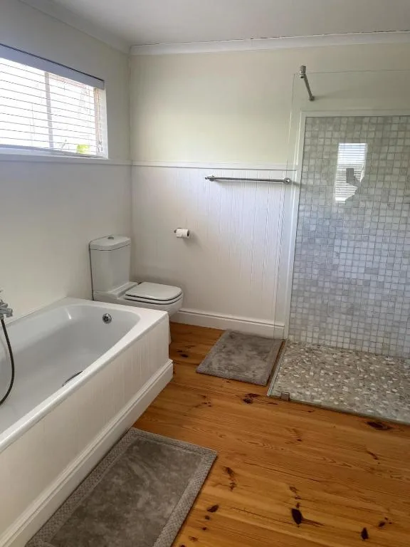 Clean bathroom with bathtub, toilet, shower cubicle and wooden floors