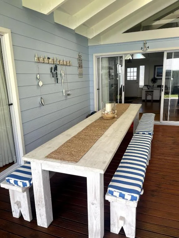 Outdoor entertaining area with long wooden table and striped cushioned seating