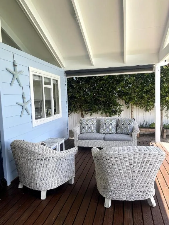 Covered deck with wicker seating and sofa overlooking garden area
