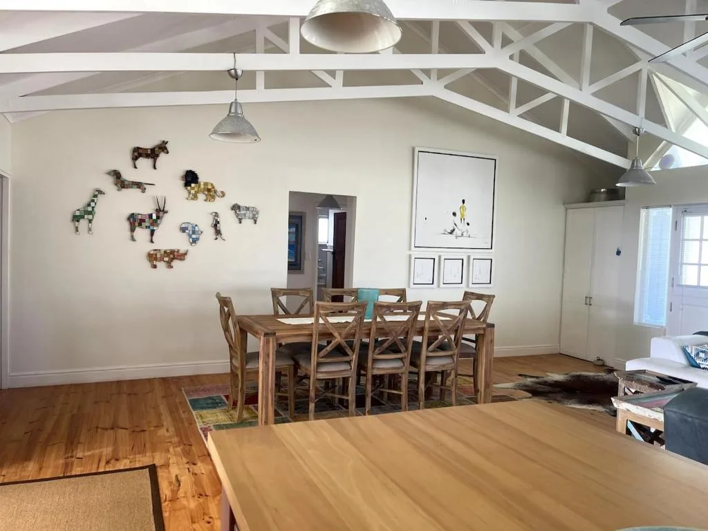 Spacious dining area with wooden table, chairs, and decorative animal wall art