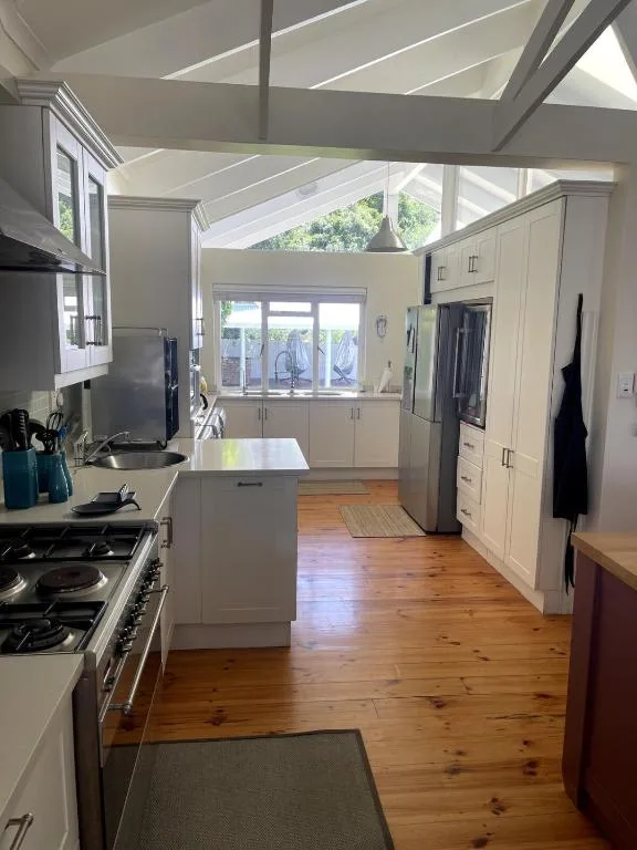 Modern kitchen with white cabinetry, gas stove, island, and skylights