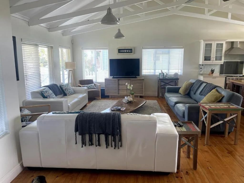 Spacious open-plan lounge with white sofas, TV, and modern furnishings