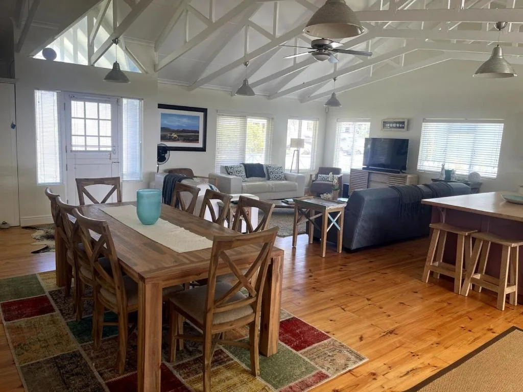 Open-plan living area with dining table, sofa, TV, and vaulted ceiling