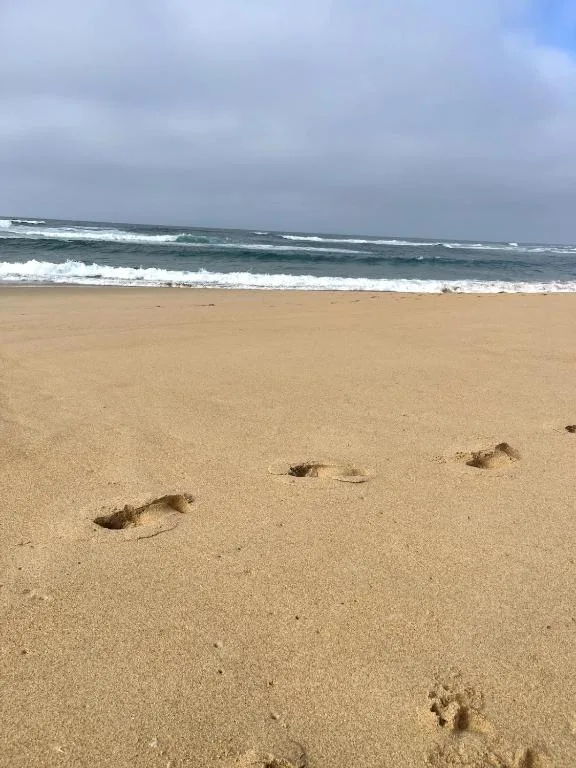 Sandy beach with ocean waves and footprints in sand