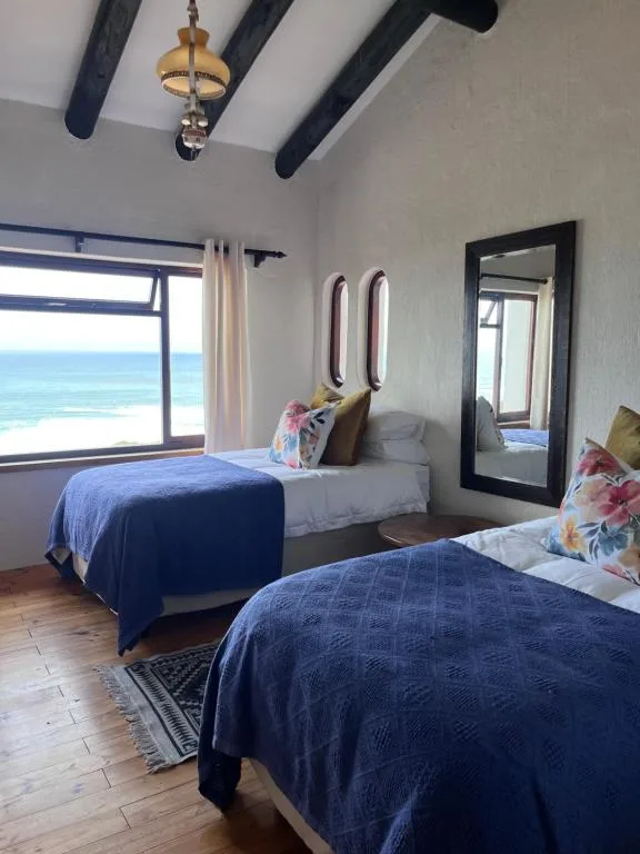 Bright bedroom with two beds and ocean views through large windows