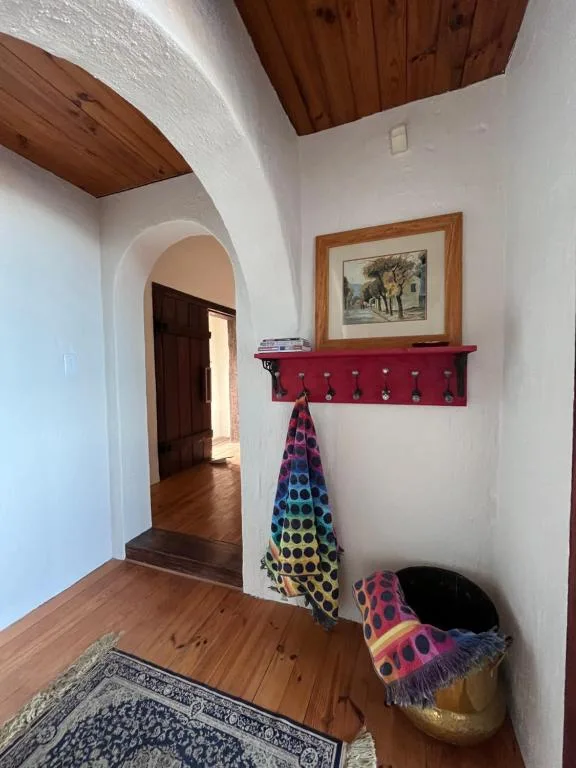 Hallway entrance with wooden beams, arched doorway, and decorative shelf