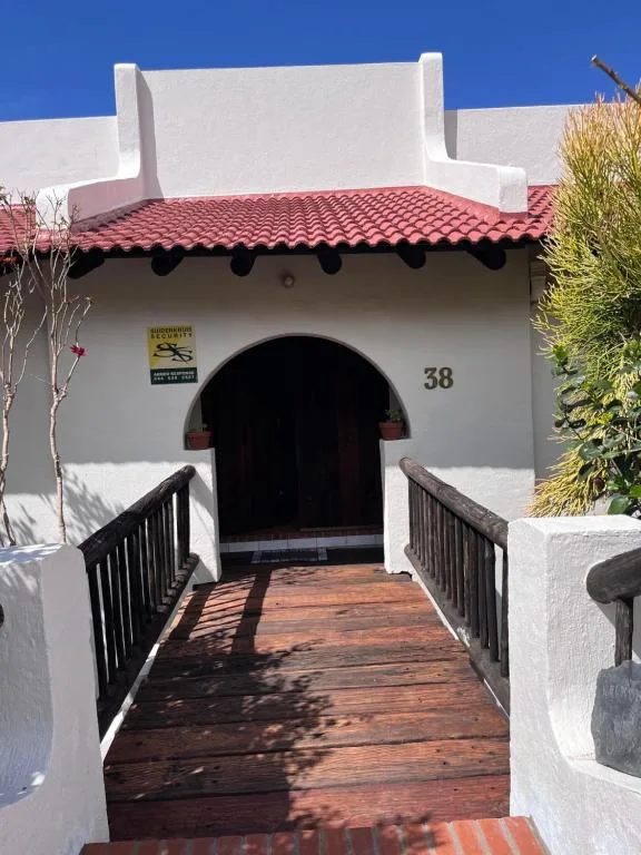 White-walled entrance with arched doorway and wooden deck approach