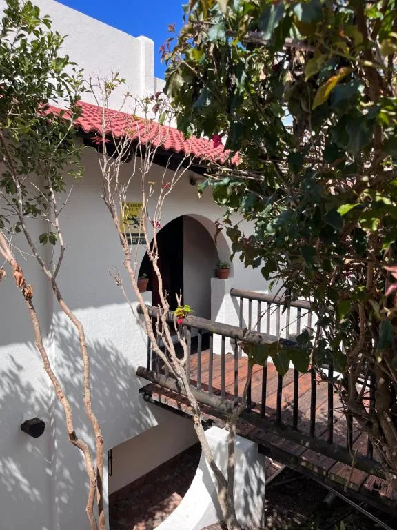 White-walled building entrance with red roof and climbing vines