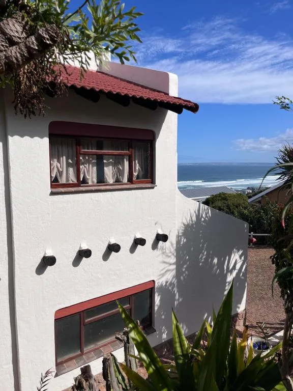 White-walled apartment building with red-tiled roof and ocean view beyond