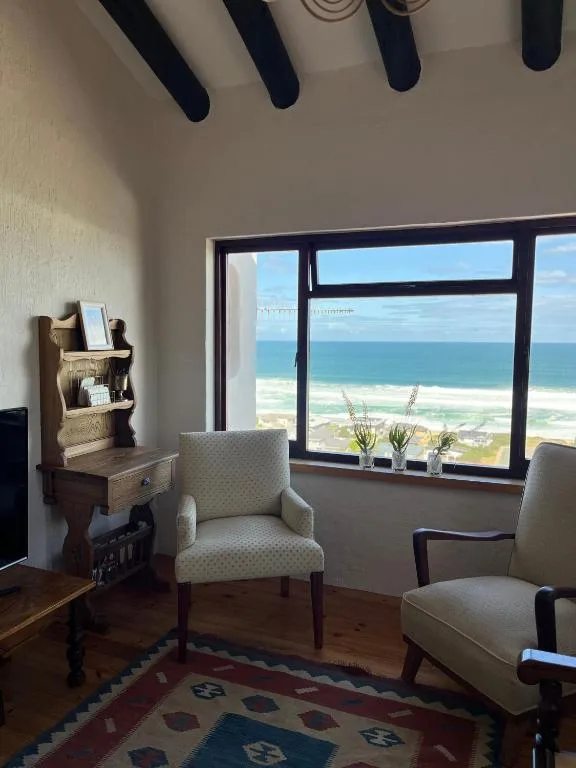 Spacious lounge with ocean view through large windows and coastal scenery