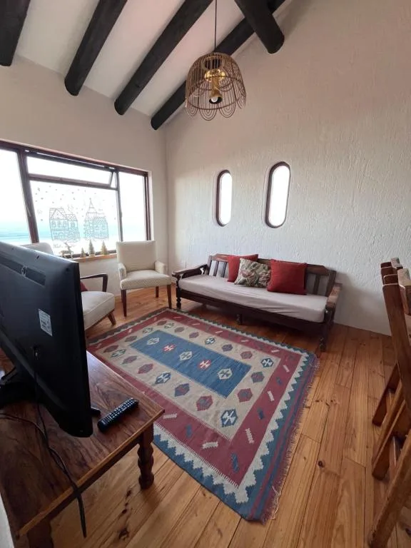 Bright living room with sofa, armchair, patterned rug, and exposed black beams