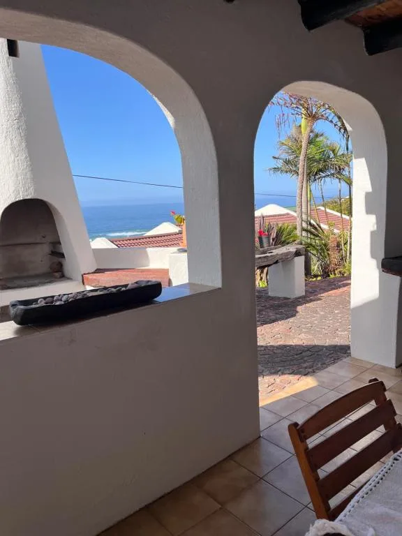 Ocean vista framed by white arched doorways and palm trees