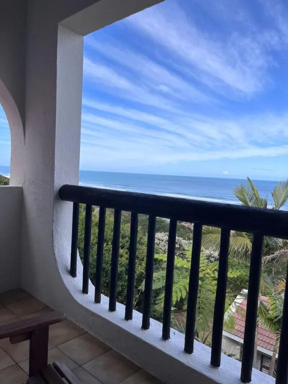 Ocean and coastal landscape vista from curved balcony with black railing