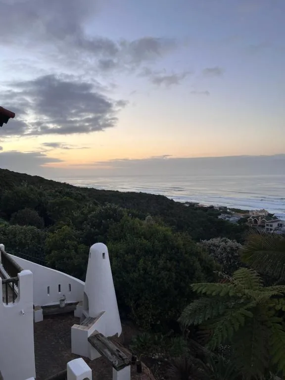 Sunset ocean view with coastal vegetation and white architecture below