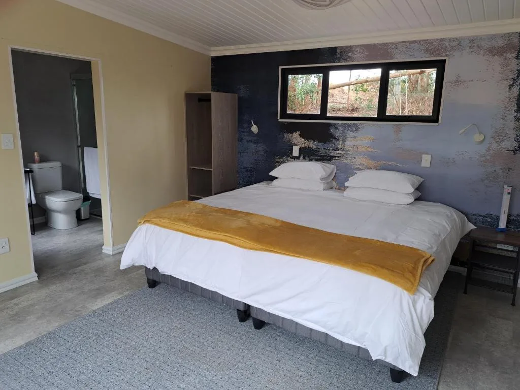 Spacious bedroom with king bed, gold throw, and ensuite bathroom access