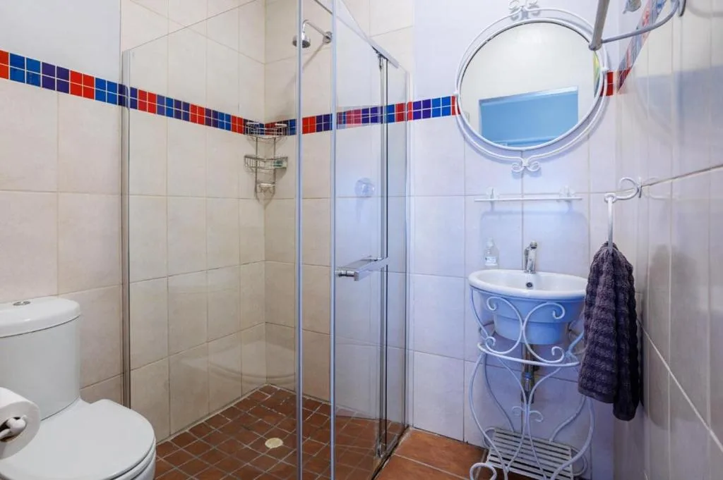 Modern bathroom with walk-in shower, pedestal sink, and toilet