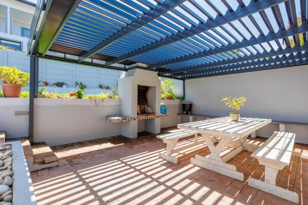 Shaded outdoor patio with wooden picnic tables and potted plants