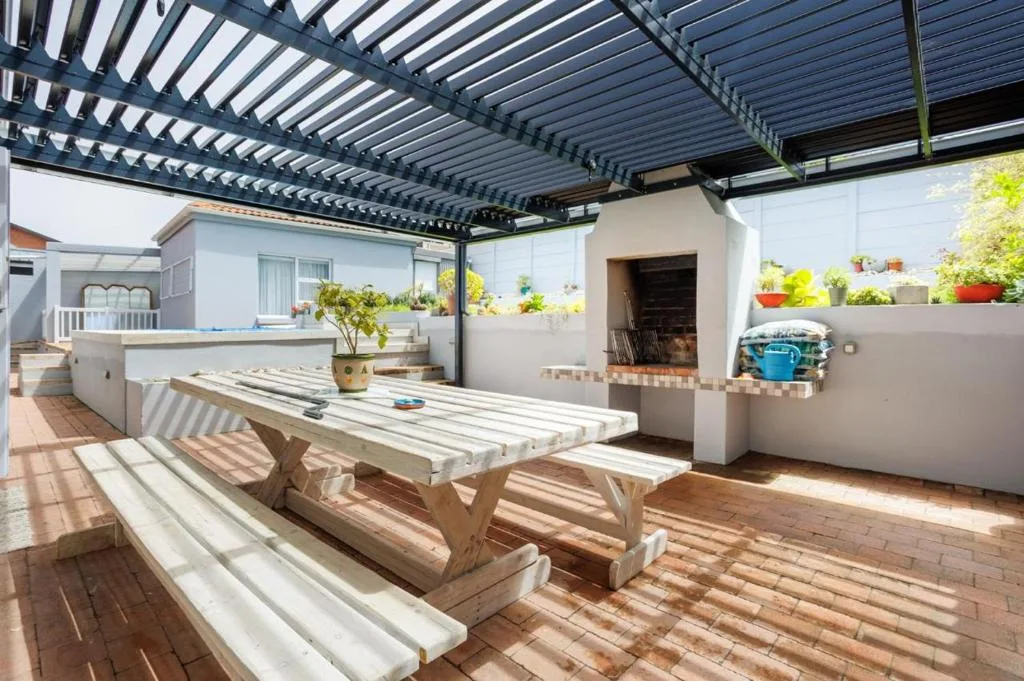Spacious outdoor patio with pergola, wooden picnic table, and potted plants