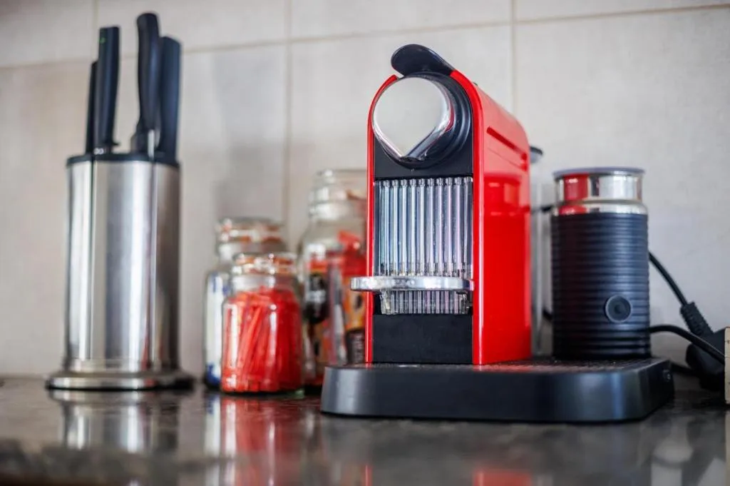 Modern kitchen appliances including red espresso machine and steel kettle