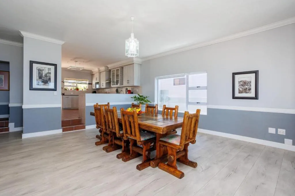 Spacious dining area with wooden table and chairs, open-plan kitchen visible