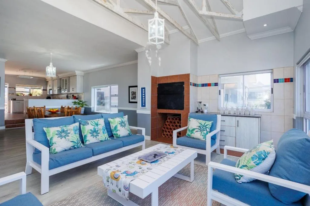 Bright open-plan lounge with blue sofas, fireplace, and skylight windows