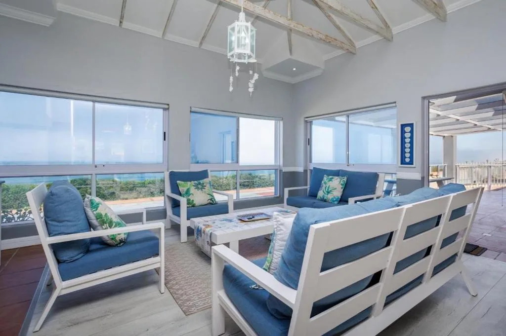 Bright lounge with blue and white seating, vaulted ceiling, and panoramic coastal views