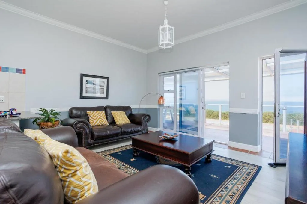 Spacious living room with leather sofas, ocean views through sliding glass doors
