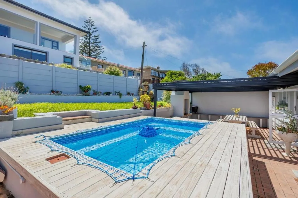 Sparkling blue swimming pool with wooden deck and garden surroundings