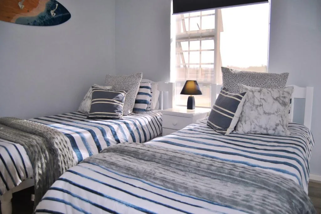 Twin bedroom with striped bedding, coastal decor, and bright window views
