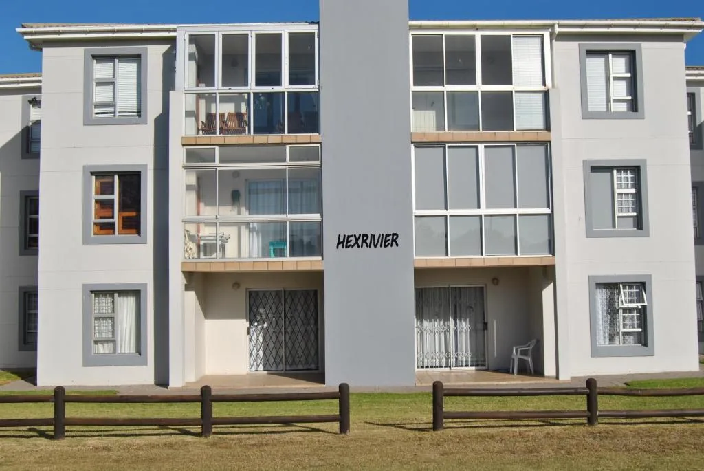 Modern white apartment building facade with large windows and wooden balconies