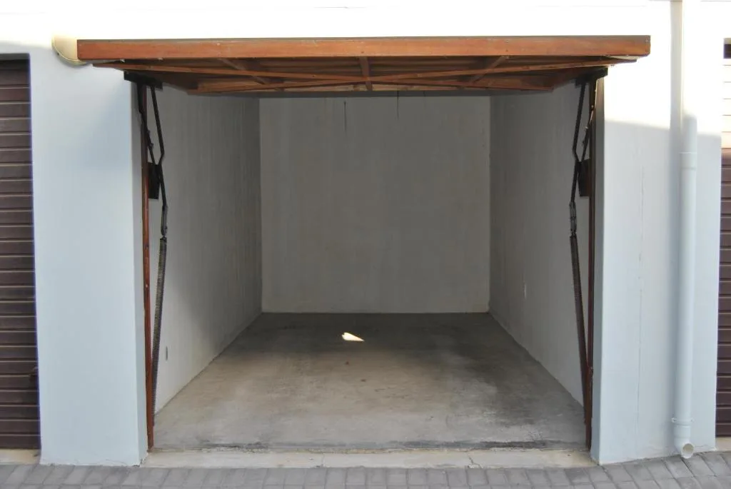 Open garage structure with wooden roof and white walls, concrete floor