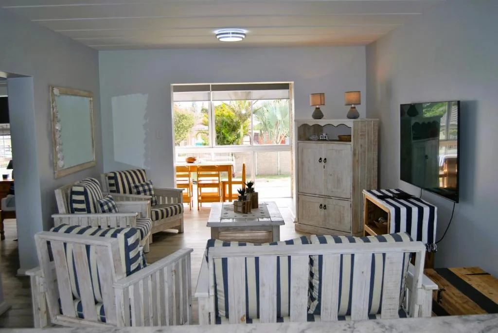 Bright lounge with striped armchairs, TV, and garden view through patio doors